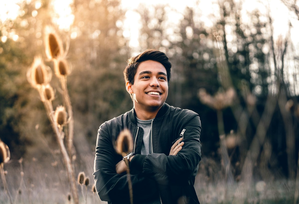 A young man smiling outdoors in warm evening light